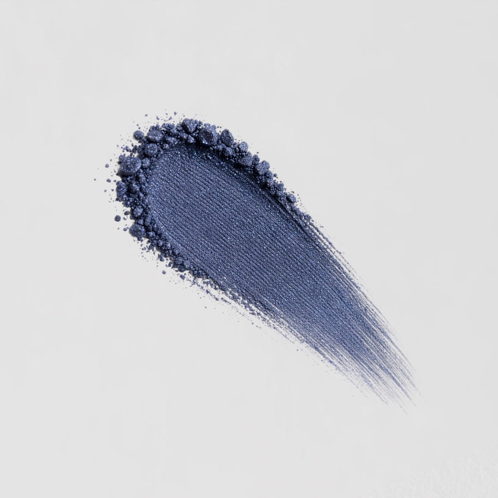 Swipe of deep blue Glow Pressed Eyeshadow showcasing its smooth, blendable texture on a white background