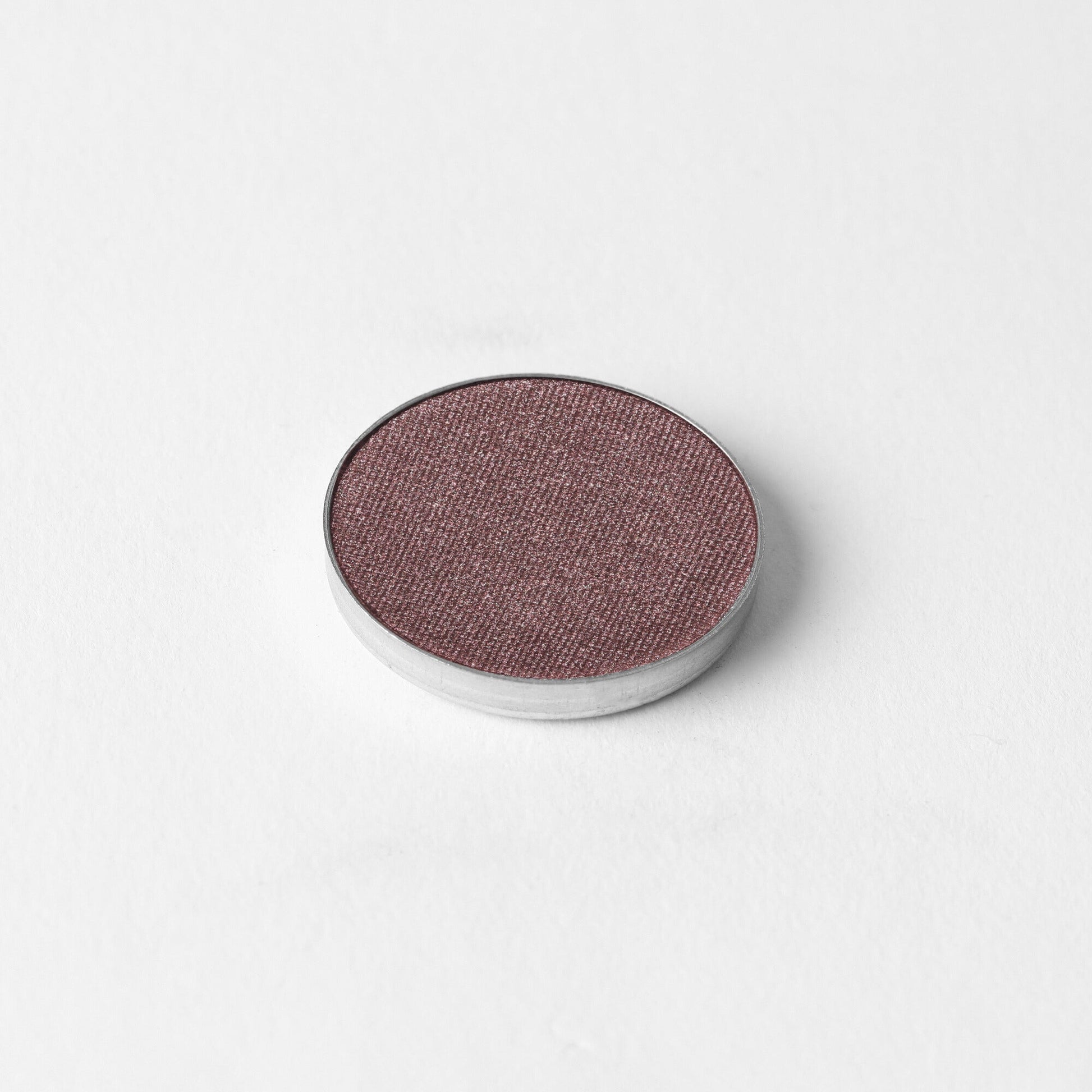 Glow Pressed Eyeshadow in a single round pan on a white background, showcasing its rich vegan pigments and smooth texture for buildable application.