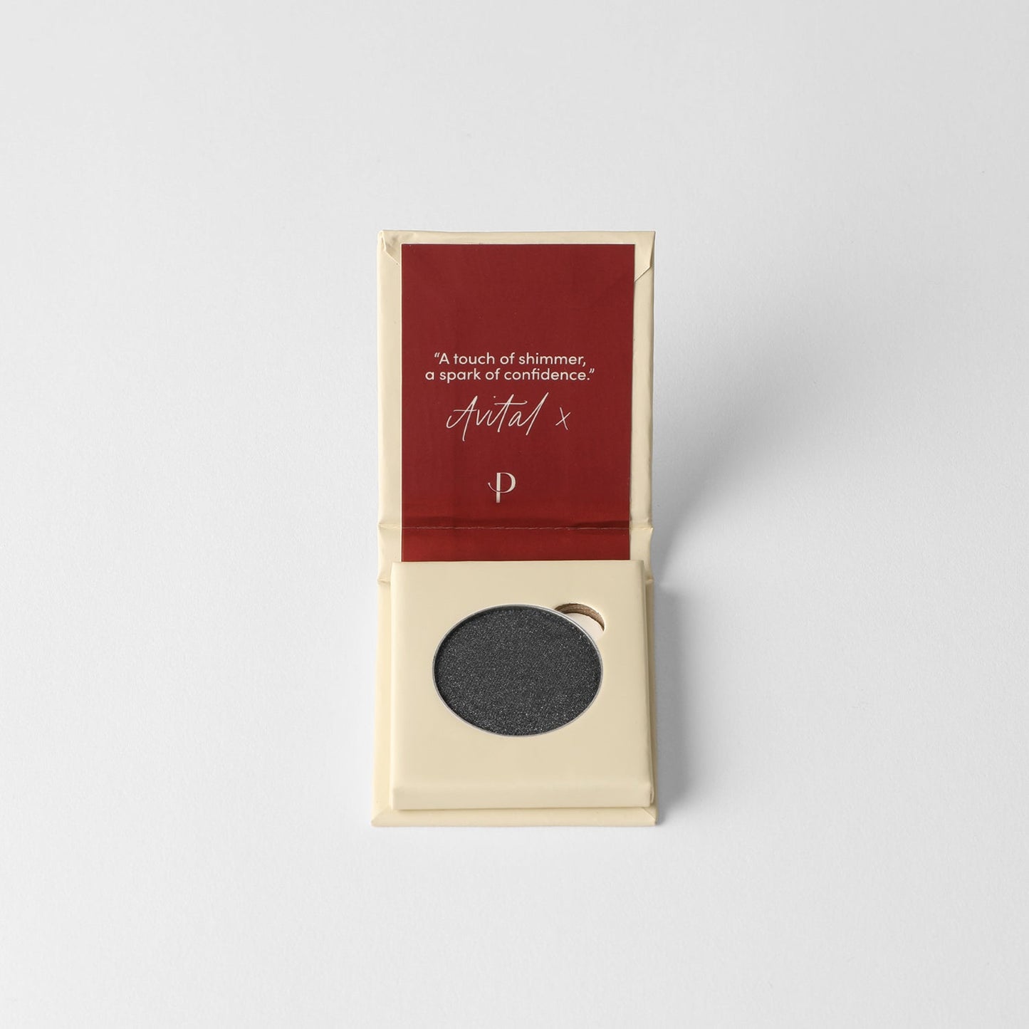 Glow Pressed Eyeshadow in open packaging showing grey shade against red and beige background.