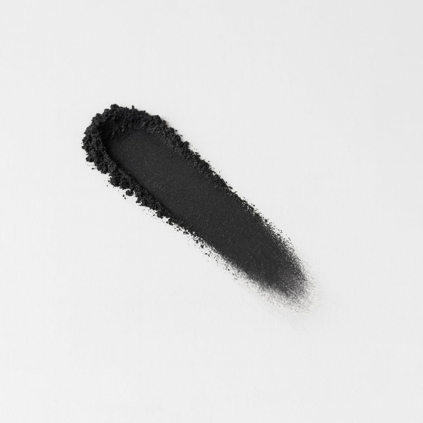 Smudge of black Glow Pressed Eyeshadow on a white background.