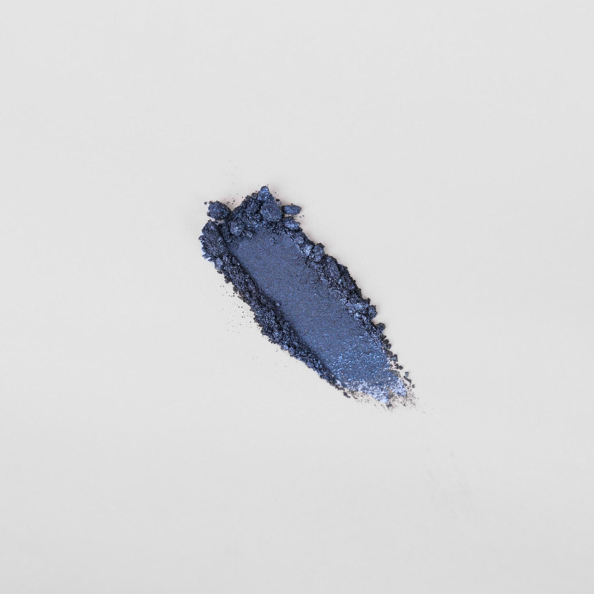 Crushed glow pressed eyeshadow pigment showcasing rich blue tone on white background.