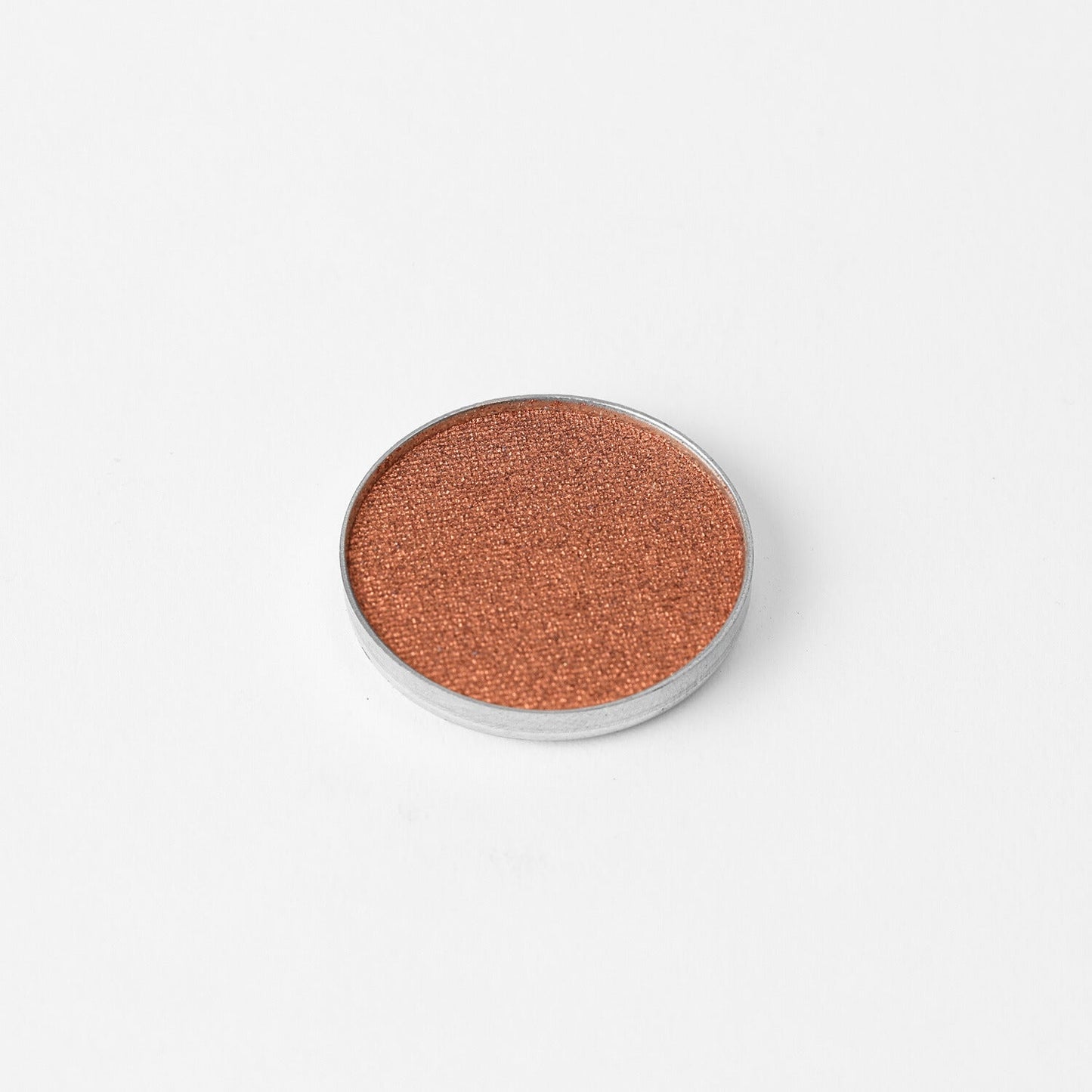Glow Pressed Eyeshadow in a metallic copper shade, showcasing its luminous vegan formula perfect for blending and layering.