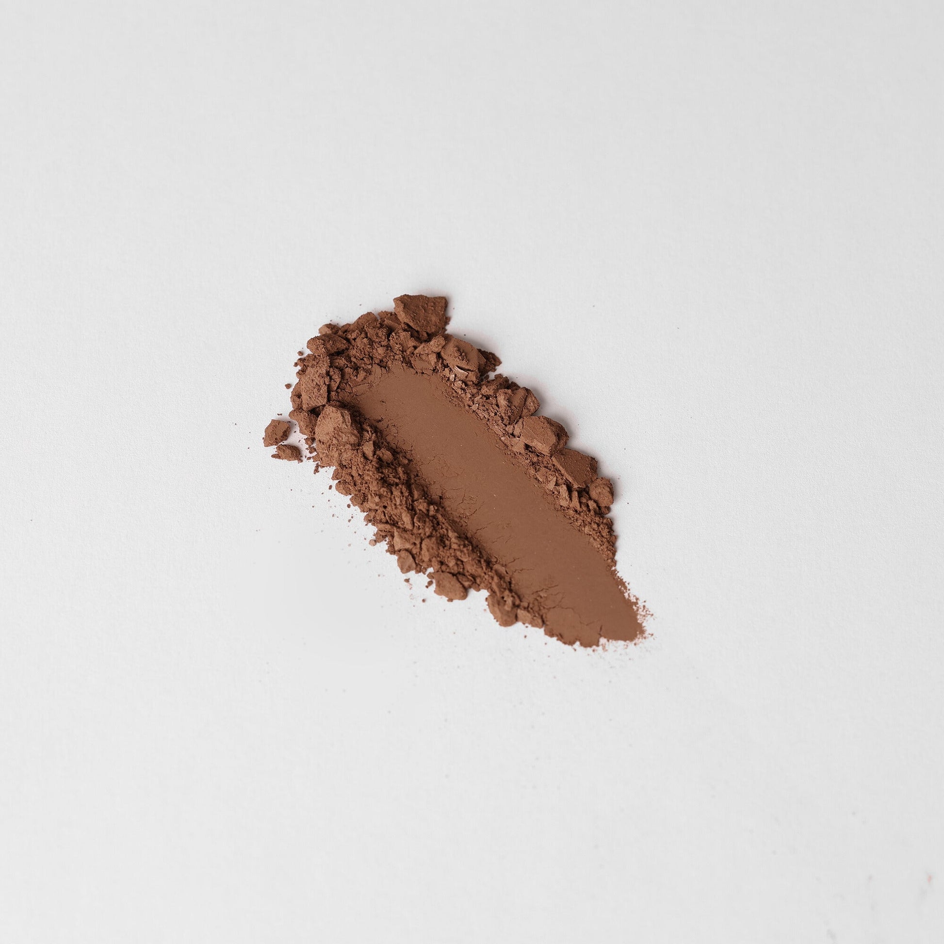 Rich brown Face Powder swatch on white background, showcasing its smooth texture and coverage benefits.