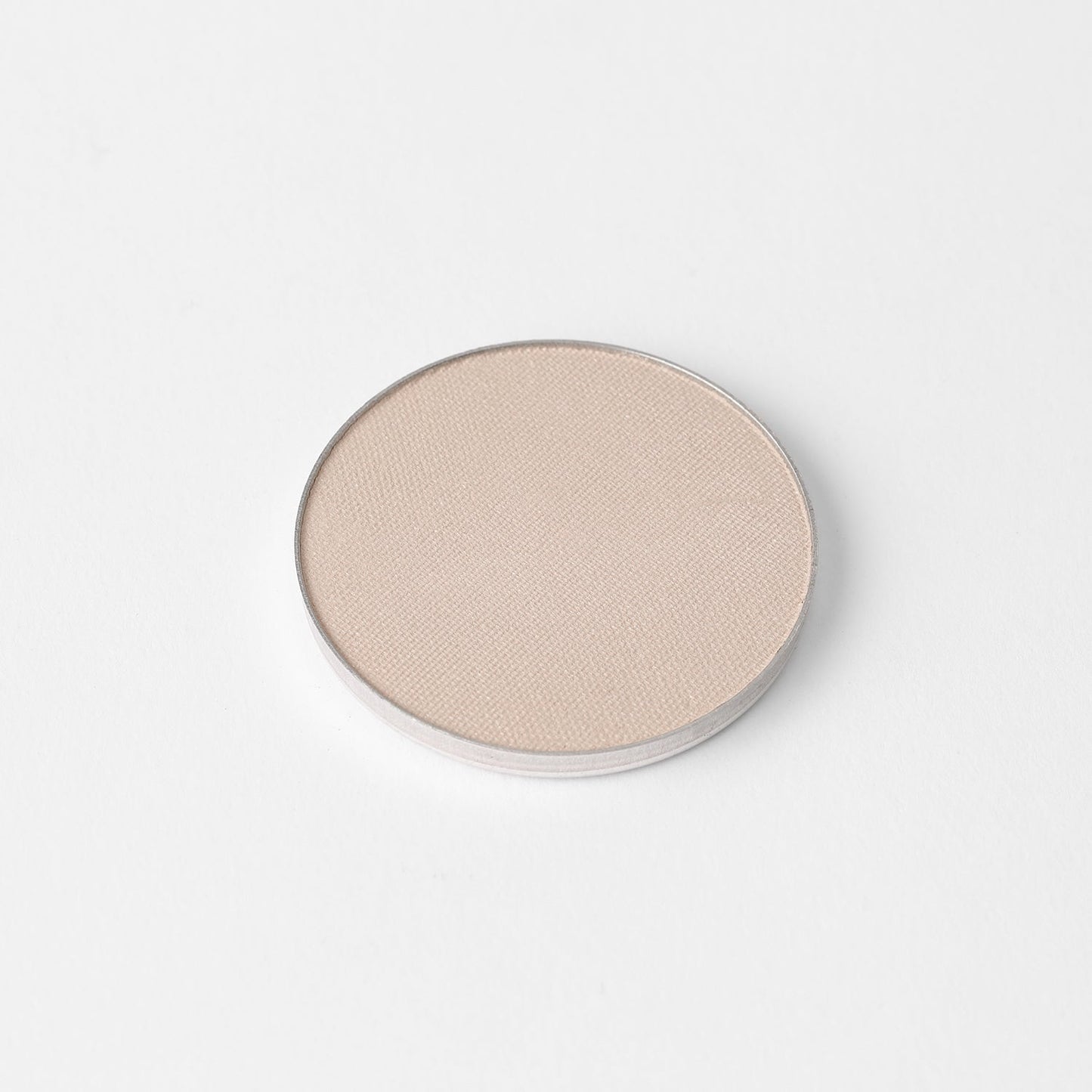 Highlighter in round silver pan for magnetic palettes, smooth finish, vegan and buildable, shown on white background.