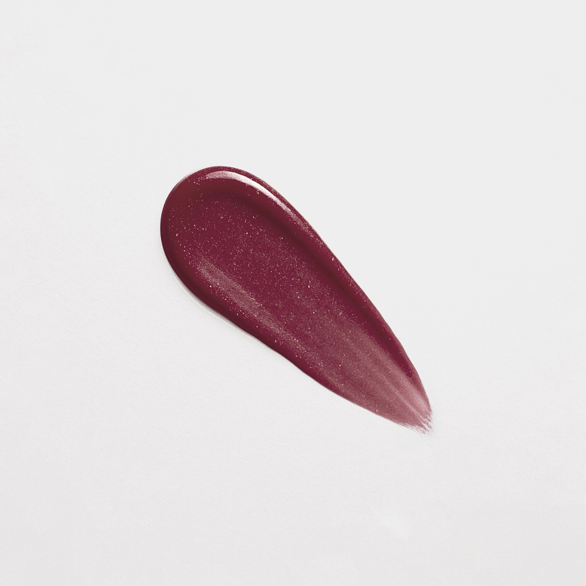 Swatch of vegan Lip Gloss Wand in rich berry shade on white background, showcasing high-shine and non-sticky finish.