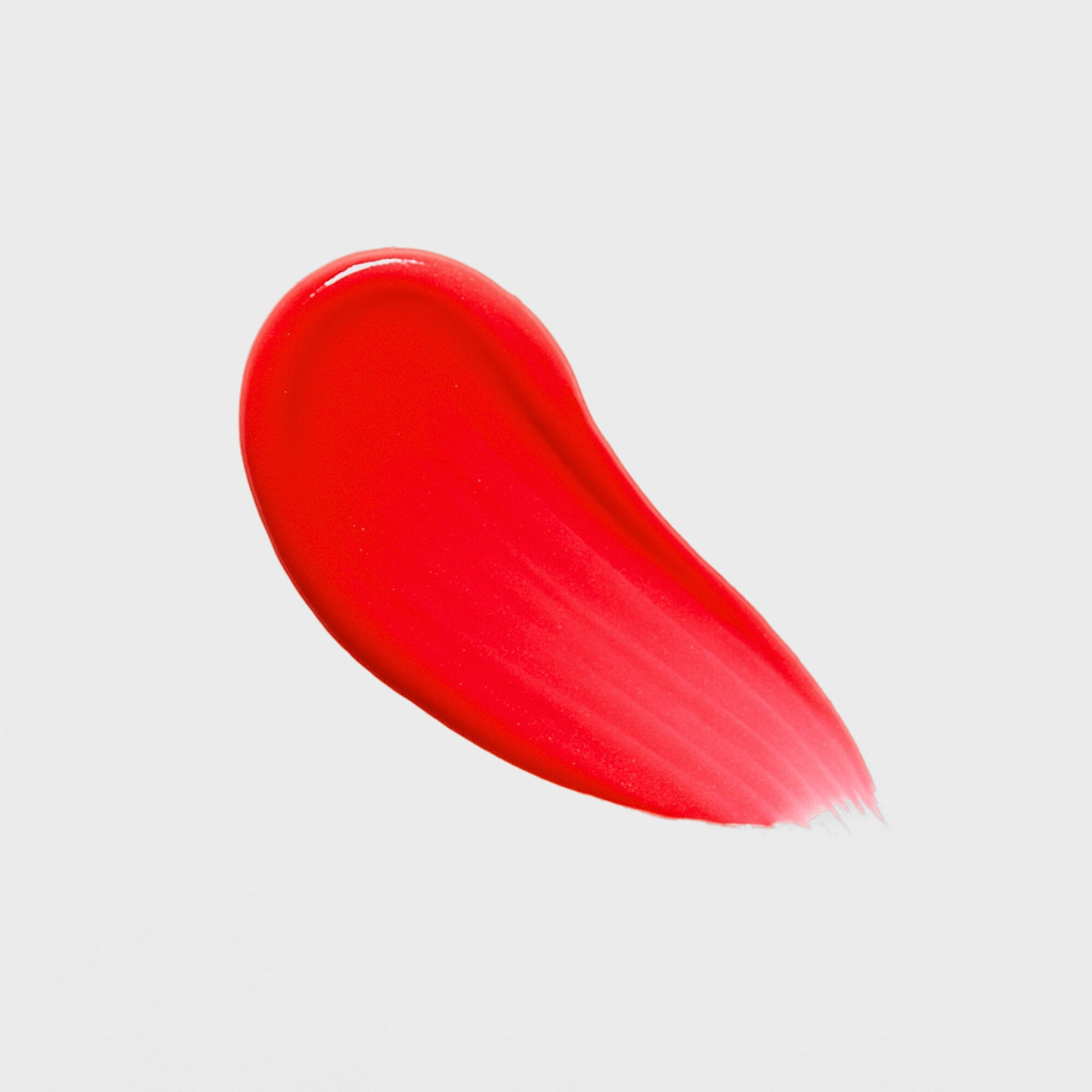 Bright red swatch of Lip Gloss Wand showcasing high-shine, vegan formula for a dimensional glow and smooth, nourished lips.