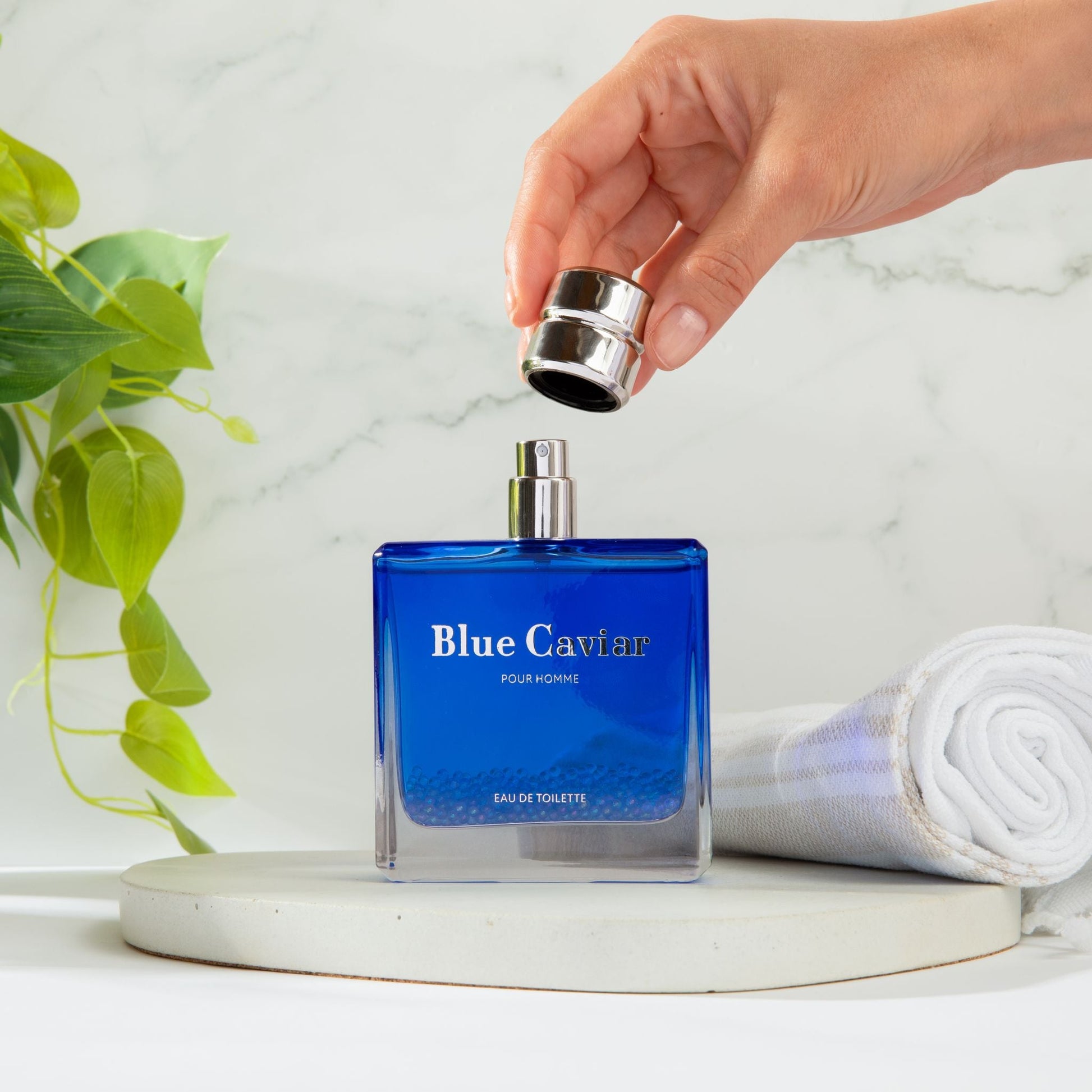 Syren - Blue Caviar perfume bottle with cap being lifted by hand, elegant fragrance for men with Italian Lemon and Lavender notes.