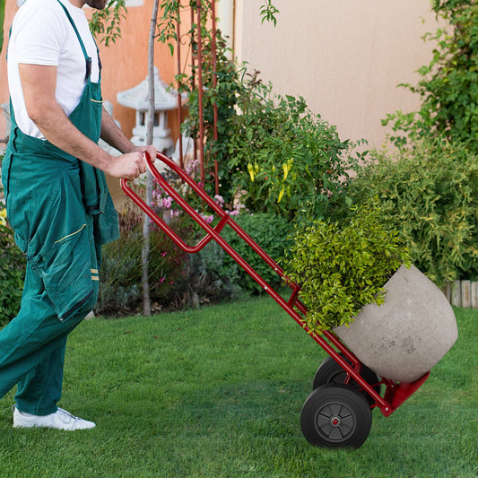 Person using a red P-Handle Sack Truck with 10 Inch Wheels and Foldable Load Area for garden landscaping.