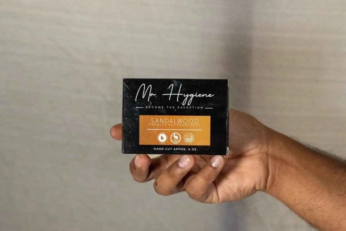 Hand holding Sandalwood Bar Soap – Classic Scent, Deep Clean packaging against neutral background