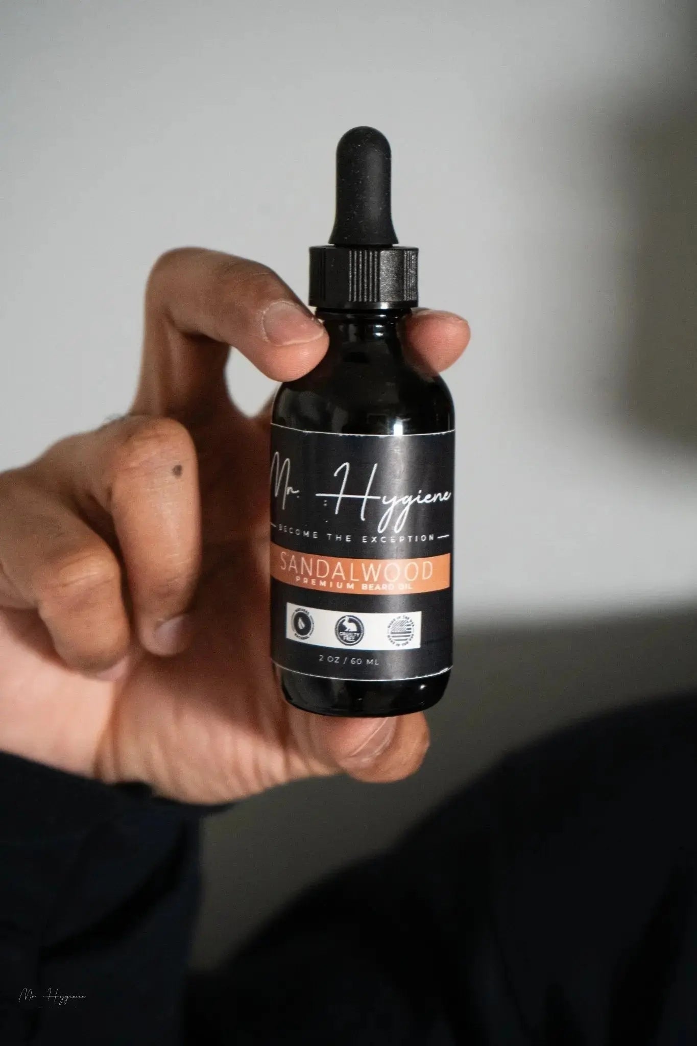 Hand holding a bottle of Sandalwood Beard Oil for Men – Smooth, Bold & Clean with dropper cap