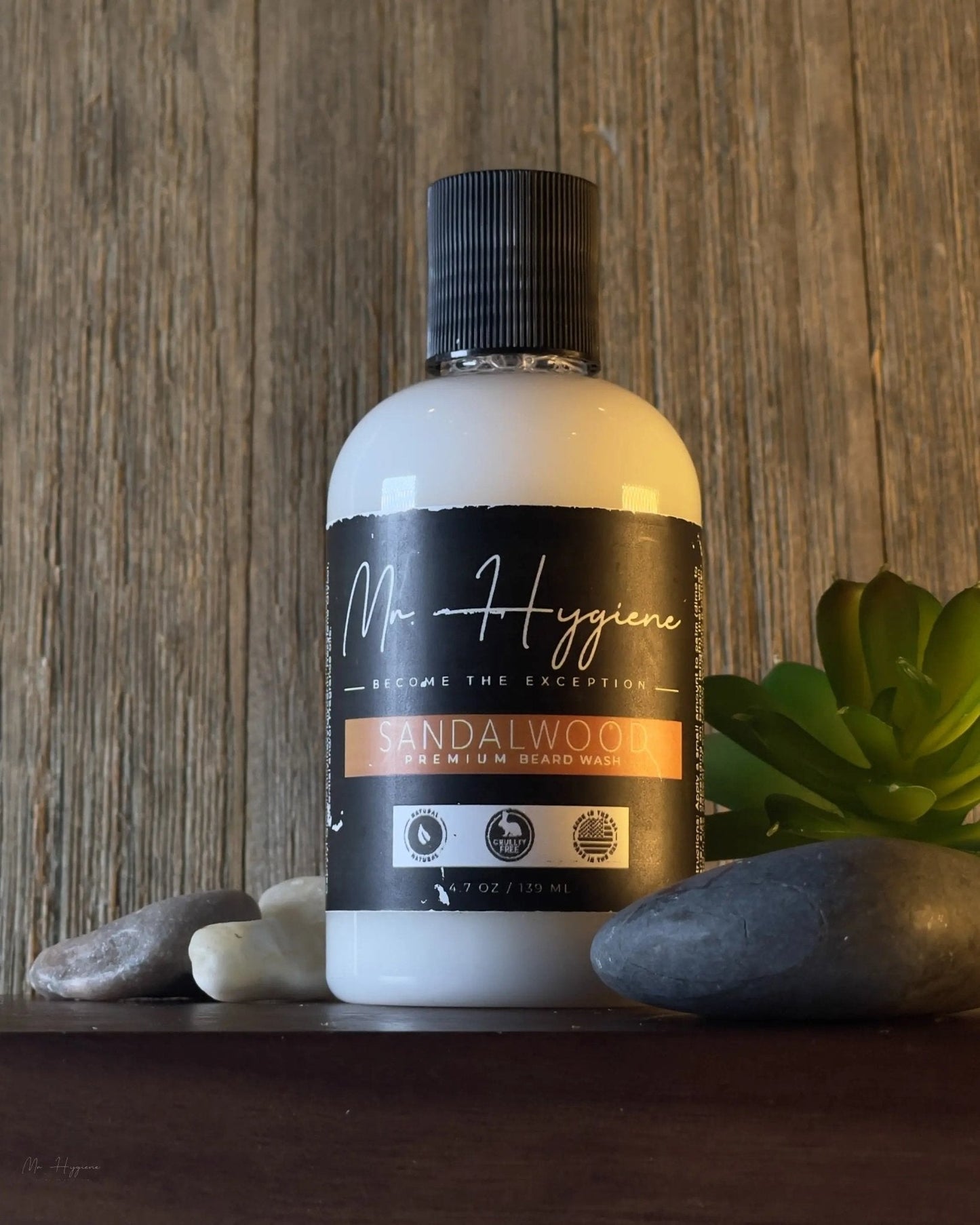 Bottle of Sandalwood Beard Wash & Conditioner on a wooden surface with stones and a plant
