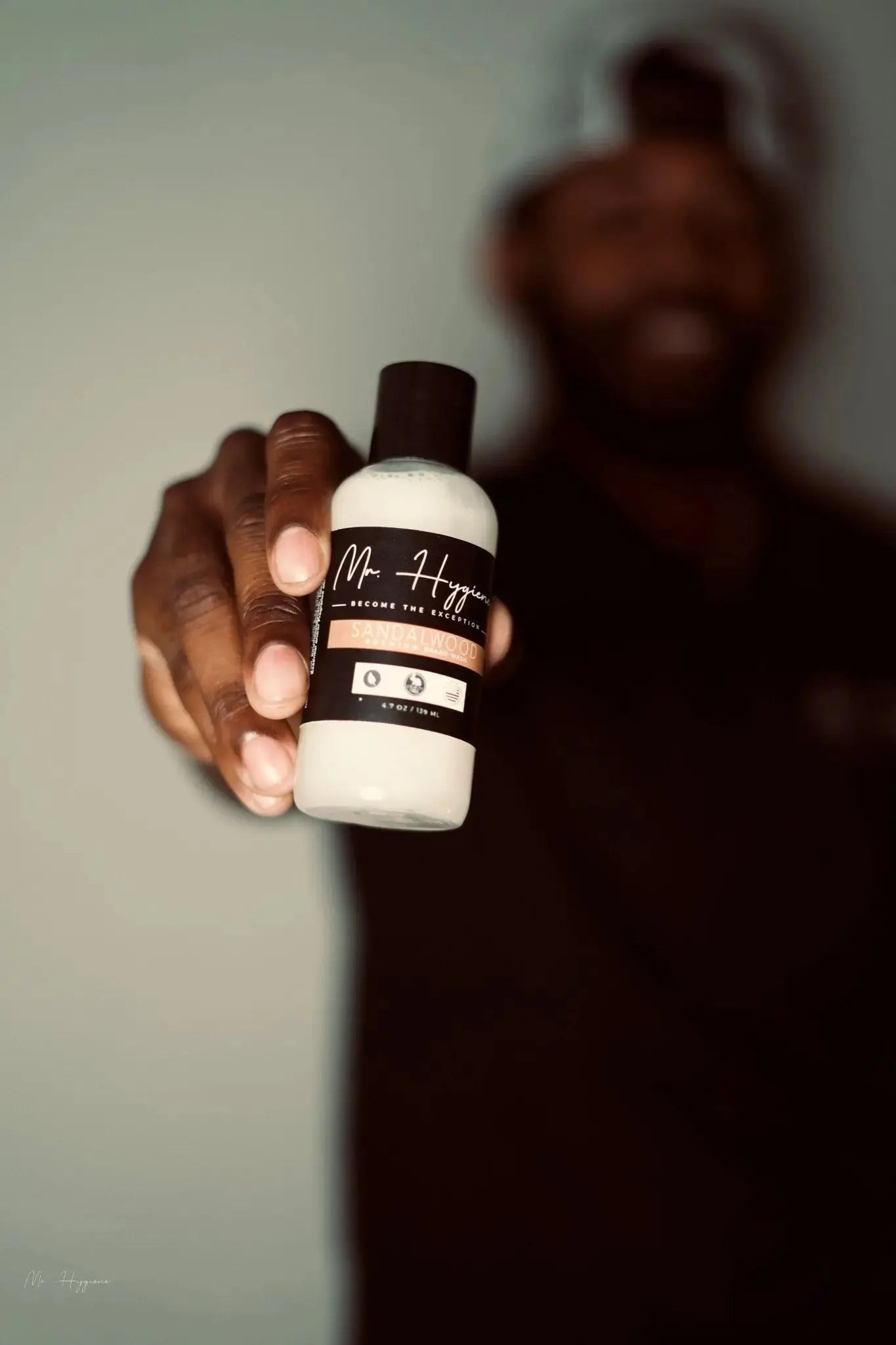 Man holding Sandalwood Beard Wash & Conditioner bottle with a subtle soothing scent for beard care and grooming routine.