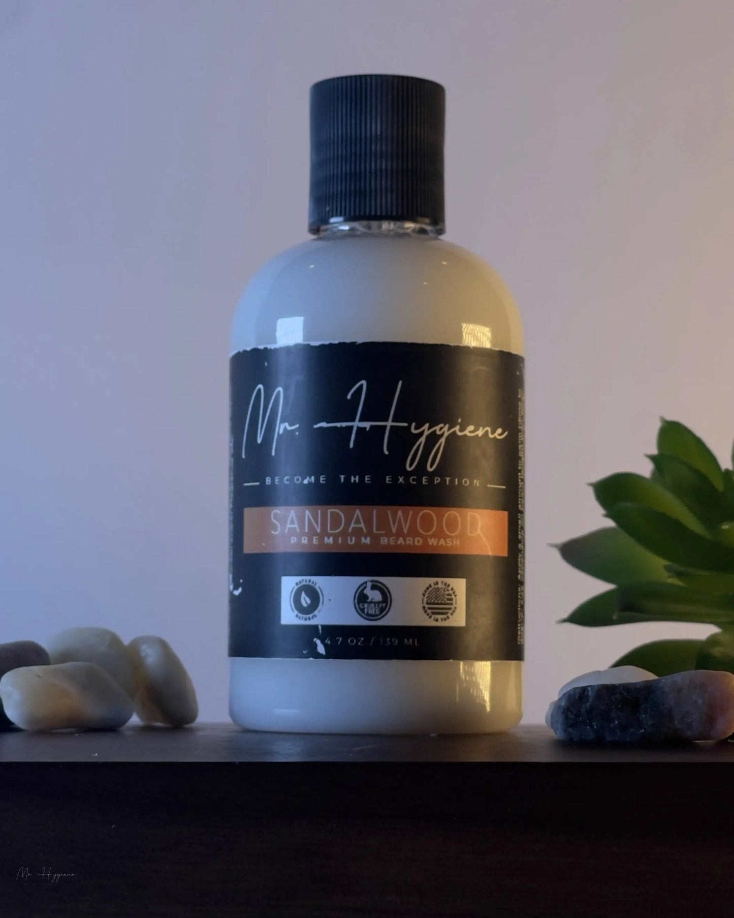 Sandalwood Beard Wash & Conditioner bottle on a shelf with stones and plant decor.