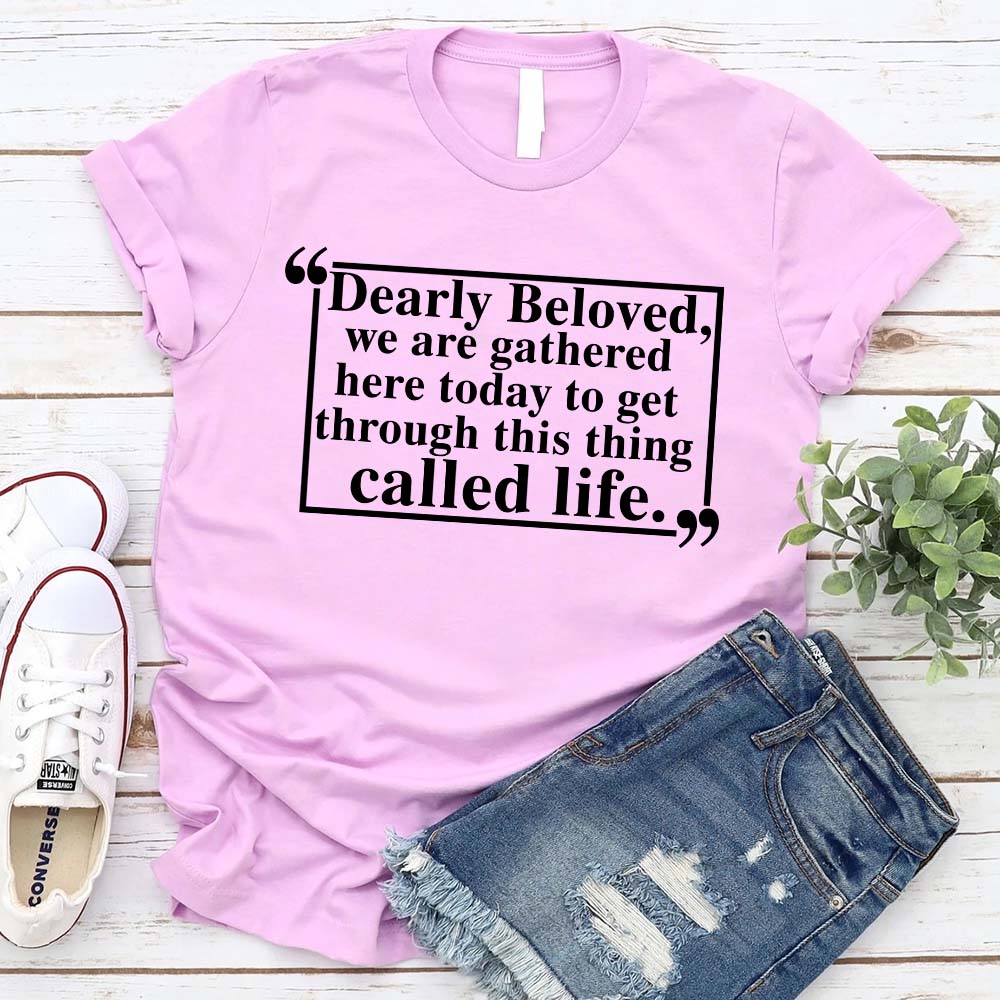 Dearly Beloved Tee Unisex Funny Quote Shirt in pink with humorous text, laid flat with denim shorts and sneakers.