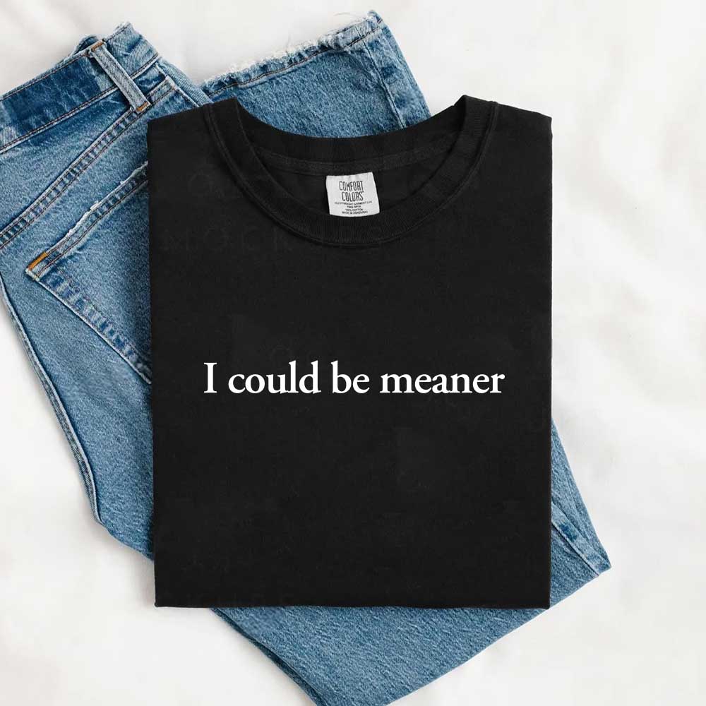 Black t-shirt with 'I Could Be Meaner' quote folded on blue jeans, representing the I Could Be Meaner Funny Sarcastic Tee.
