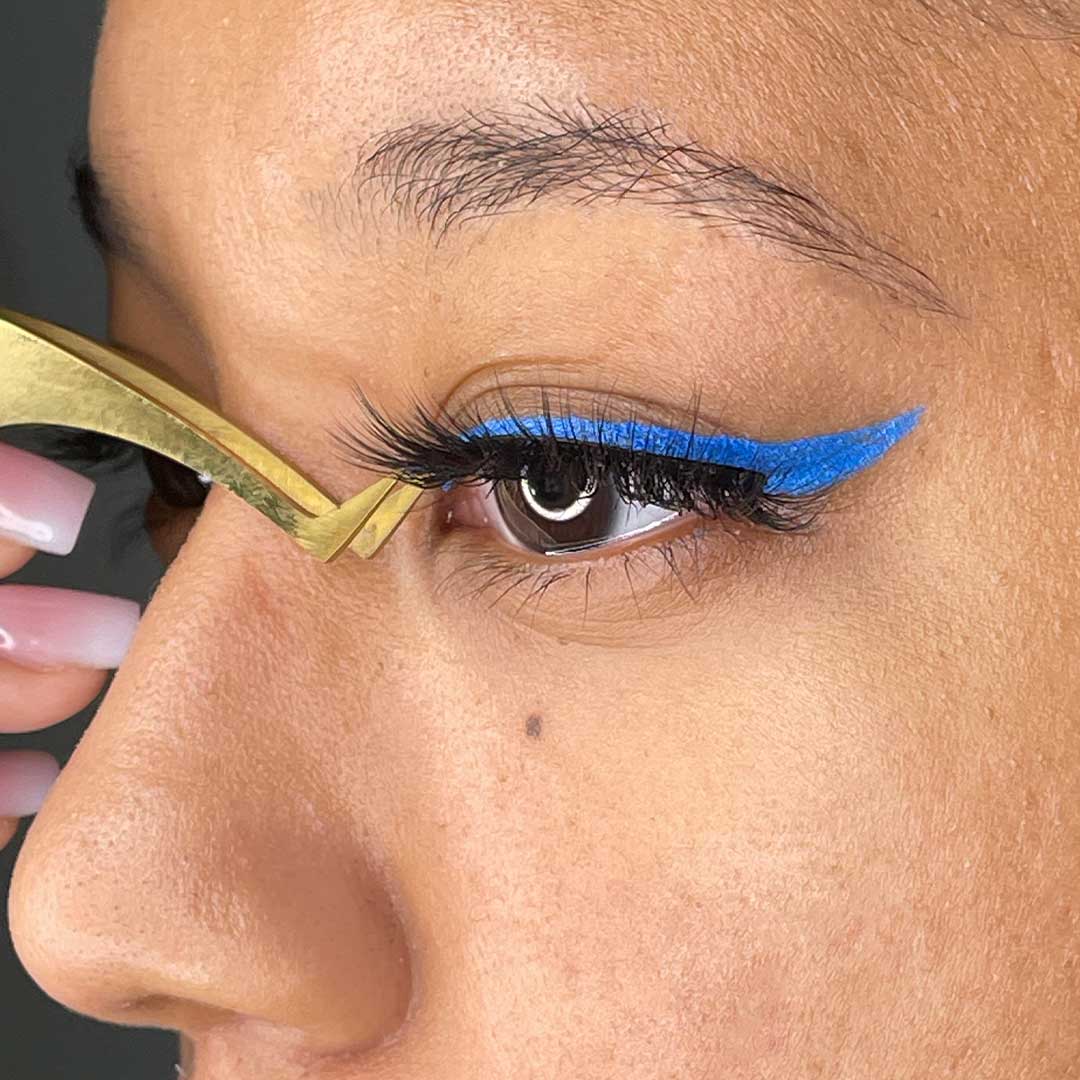 Close-up of woman applying The Threesome | 3 Way Strip Lash Set with blue eyeliner for dramatic look.