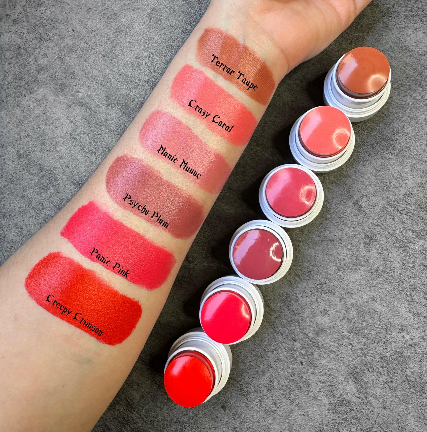 Arm swatched with various shades of cream blush, featuring Creepy Crimson, a deep red, vegan and cruelty-free, in smooth satin-matte finish.