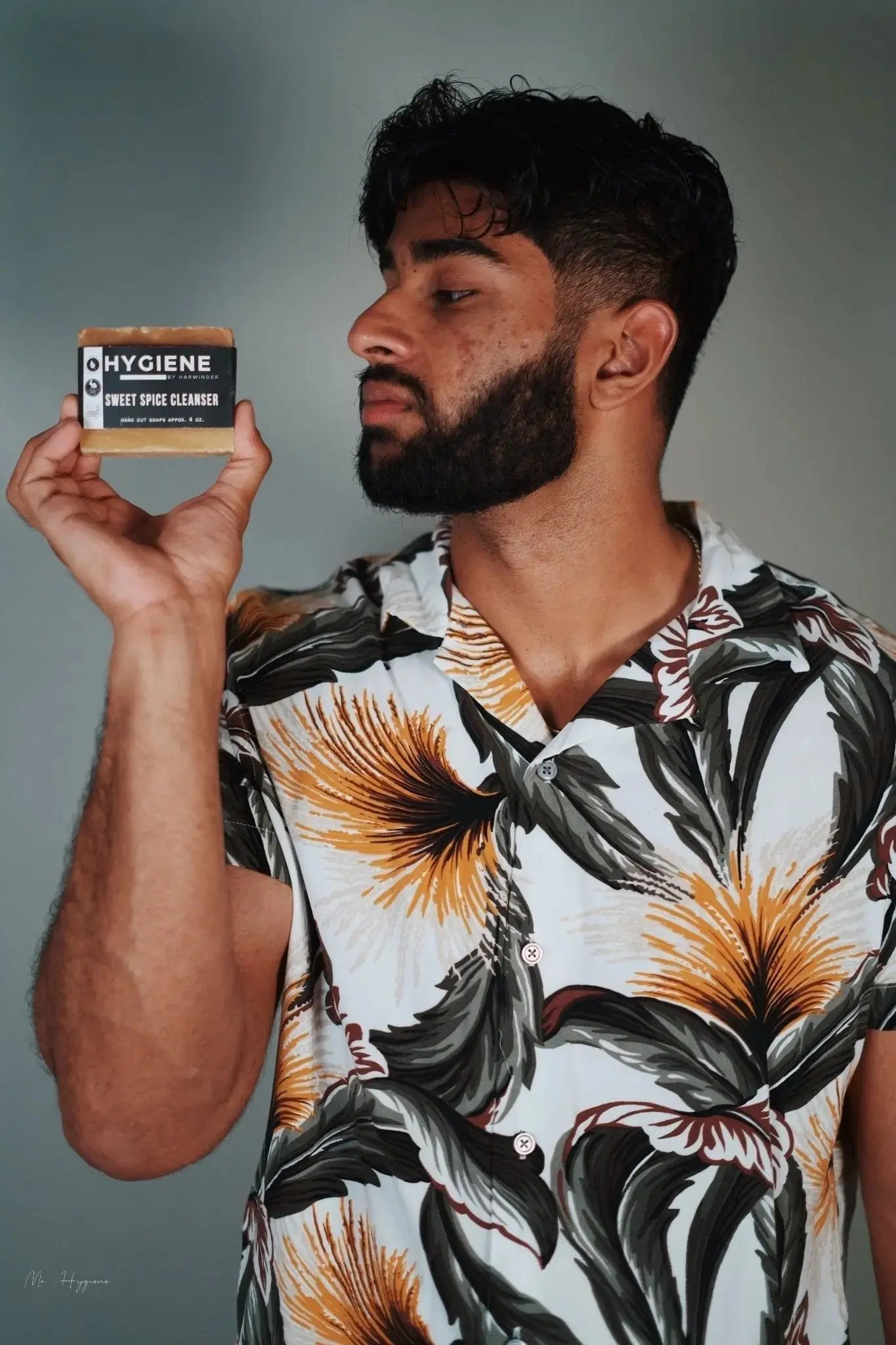 Man holding Sweet Spice Cleanser Luxury Mens Soap, showcasing packaging with floral shirt contrast.
