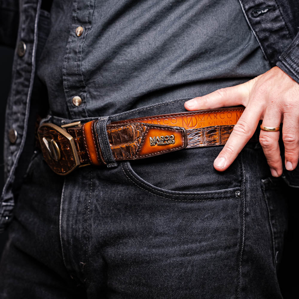 Model wearing Texas Belt Aged Brown made of caiman crocodile skin and calf leather with branding detail, enhancing western style.