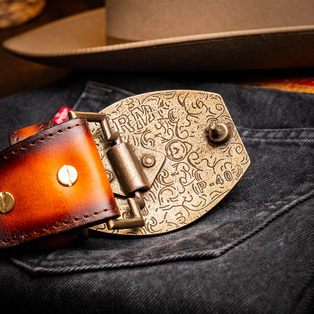 Close-up of Texas Belt Aged Maple with ornate buckle on denim fabric, showcasing caiman crocodile skin and calf leather craftsmanship.
