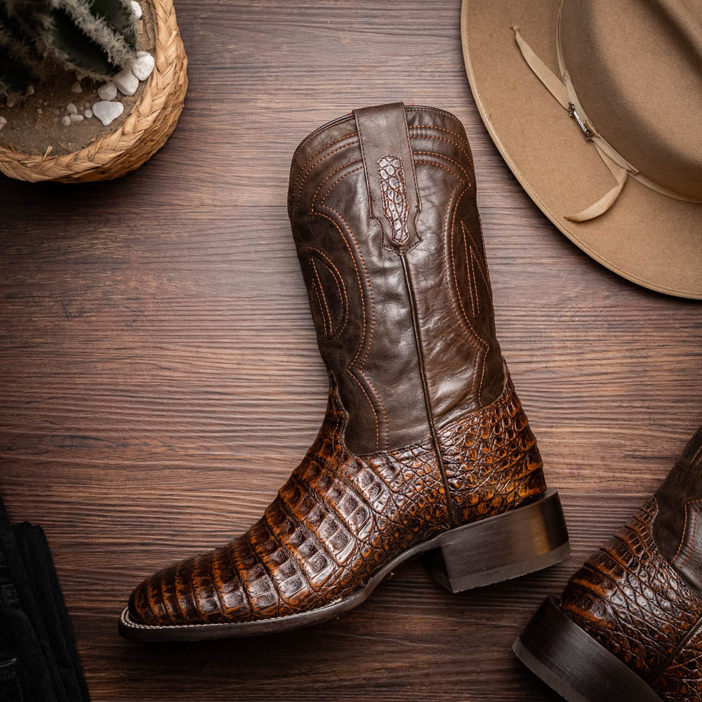 Tucson Aged Brown cowboy boot made from genuine caiman belly skin with a square toe design on a wooden background.