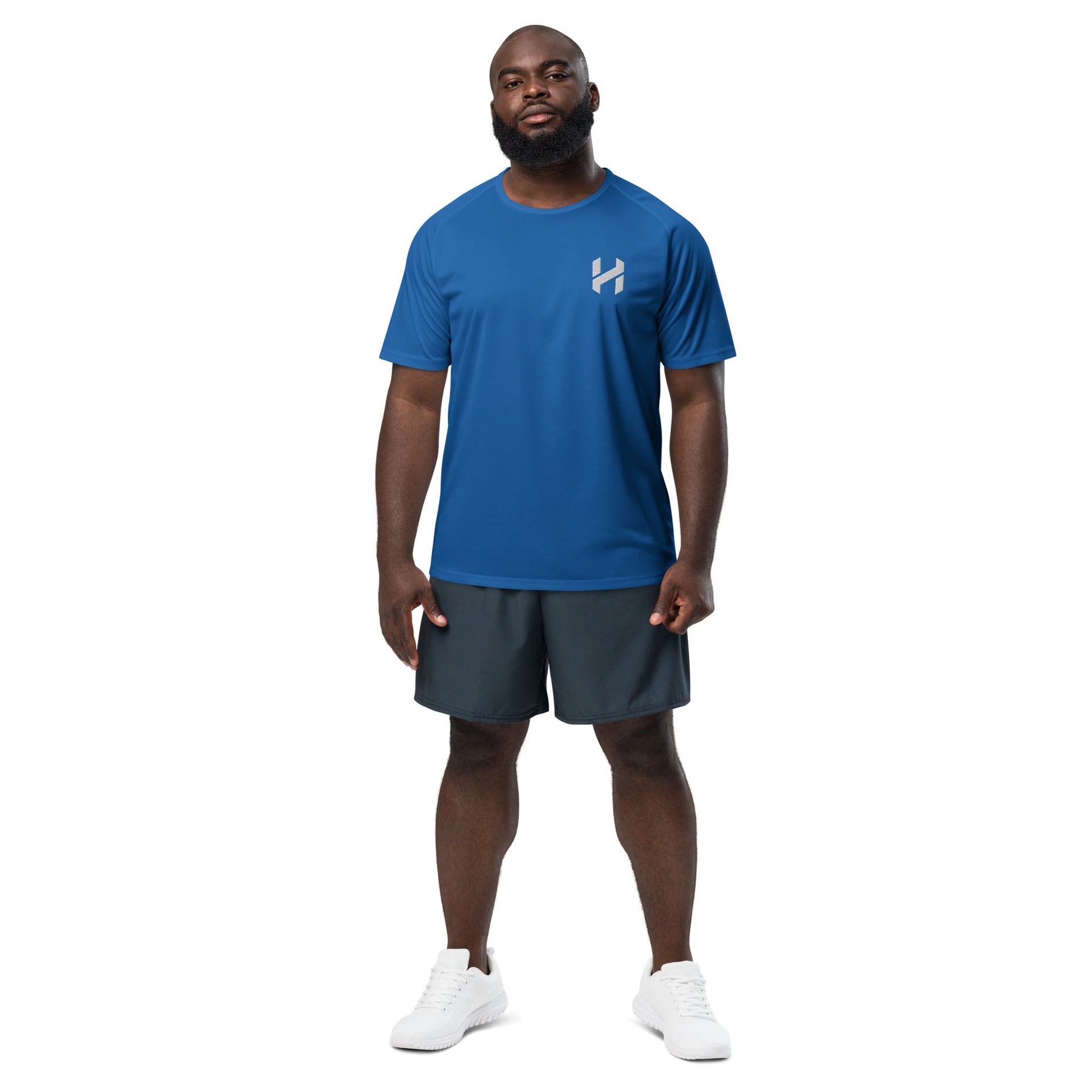 Man wearing blue athletic shirt and black shorts, standing against a white background. Ideal for workouts and sports activities.