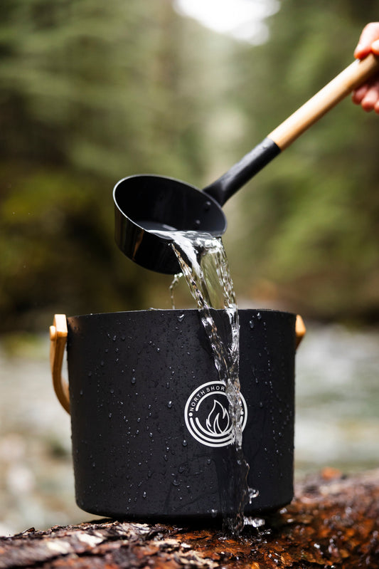 5L Black Aluminum Sauna Bucket and Ladle Set with Elegant Bamboo Handles in a natural setting