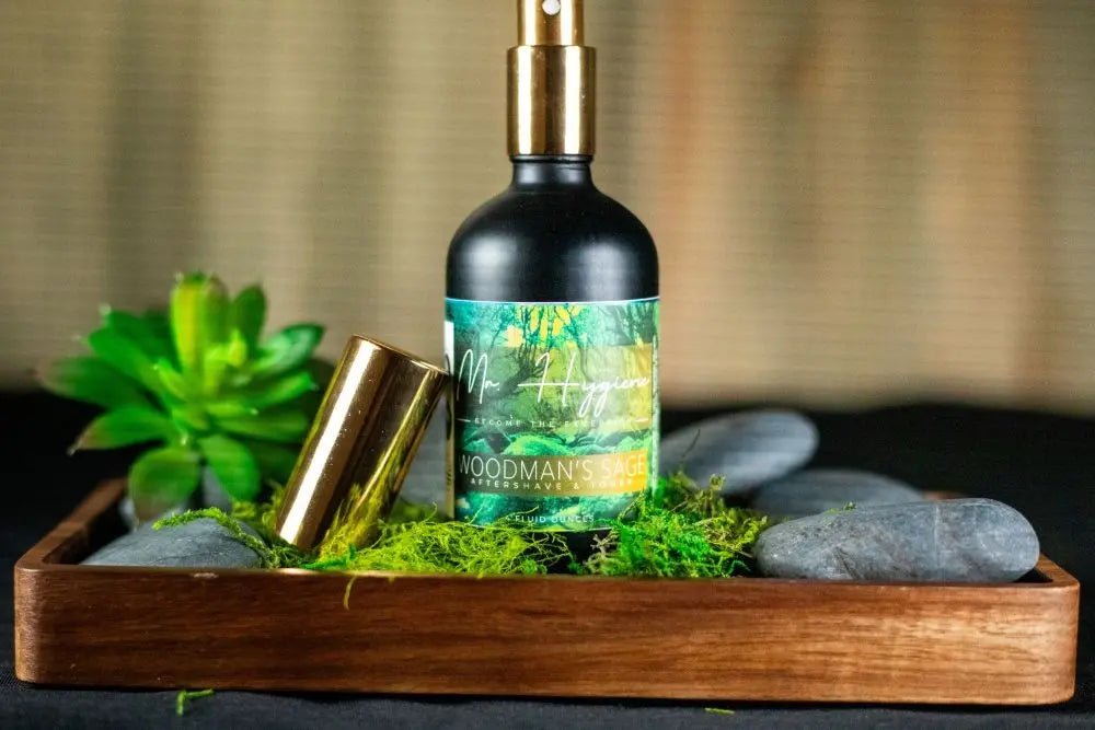 Woodman's Sage Mens Aftershave & Toner bottle on wooden tray with pebbles and greenery, offering a refreshing and nourishing grooming experience.